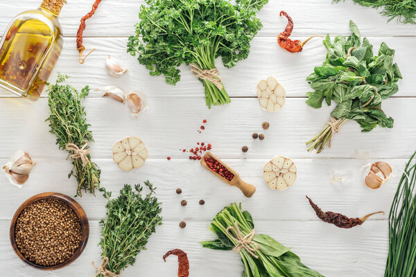top view of green herbs and spices on white wooden table