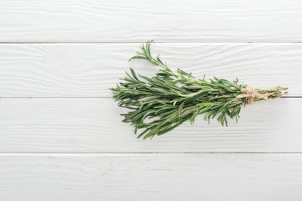 top view of fresh green rosemary on white wooden table