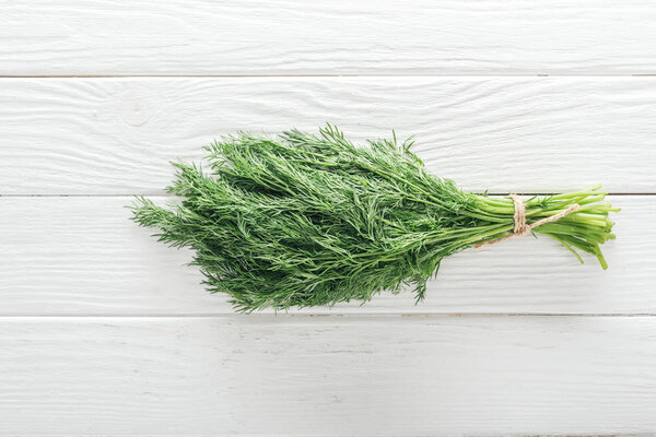 top view of fresh green dill on white wooden table