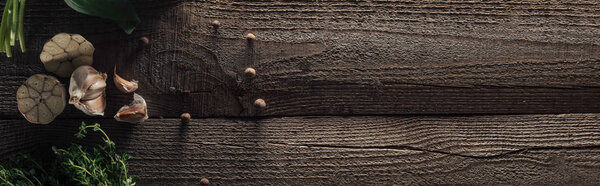 panoramic shot of garlic cloves and black pepper on wooden rustic table