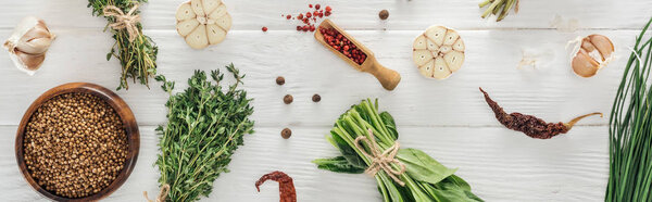panoramic shot of green herbs and spices on white wooden table