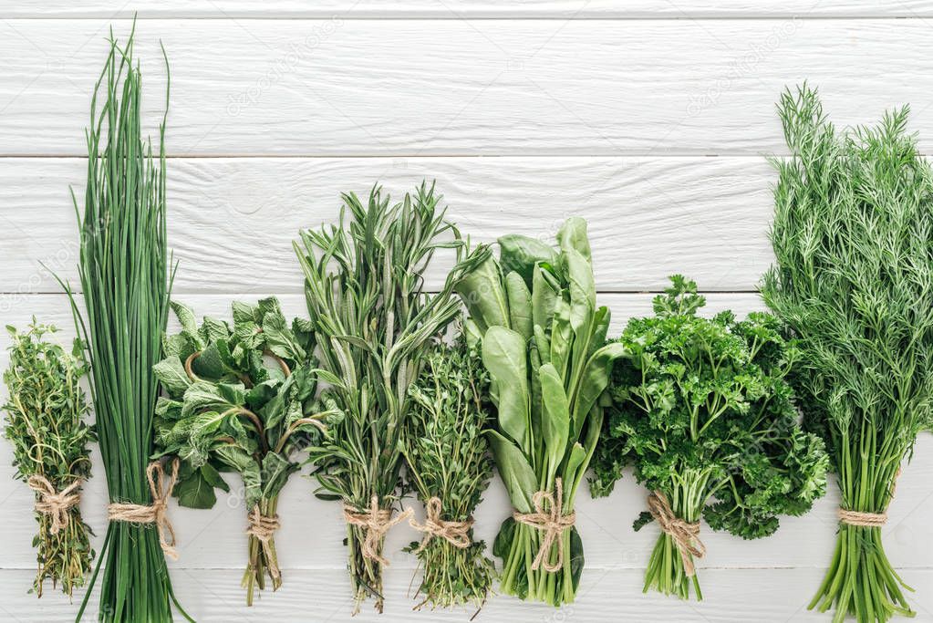 top view of various green herbs on white wooden table