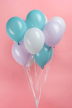 Pembe arka planda beyaz, mavi ve mor parti balonları