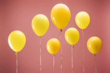 Pembe arka planda sarı balonlar, parti dekorasyonu