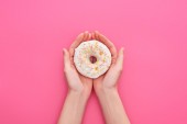 partial view of woman holding white glazed doughnuts with sprinkles on pink background