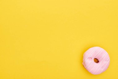 top view of tasty pink glazed doughnut on bright yellow background clipart