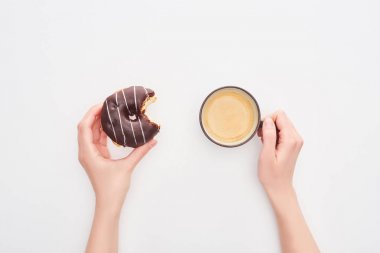 beyaz arka plan üzerinde lezzetli sırlı ısırılmış çikolatalı çörek ve kahve fincanı tutan kadın kırpılmış görünümü