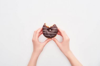 cropped view of woman holding tasty glazed bitten chocolate doughnut on white background clipart