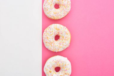 beyaz ve pembe arka plan üzerine serpiştirilmiş sırlı çörekler üst görünümü