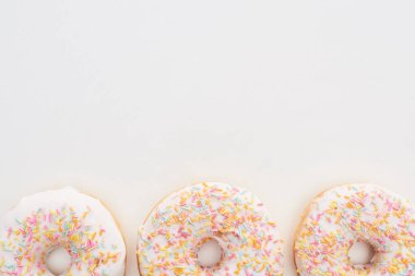 top view of white glazed doughnuts with sprinkles on white background clipart