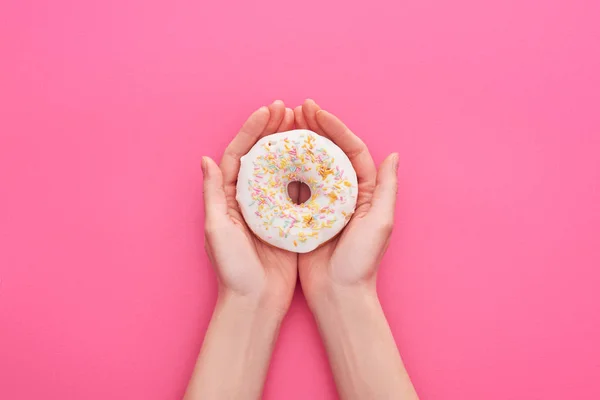 部分视图的妇女拿着白色釉面甜甜圈洒在粉红色背景 — 图库照片