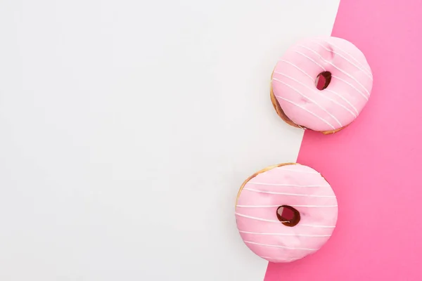 白色和粉红色背景上釉面粉红色甜甜圈的顶视图 带复制空间 — 图库照片