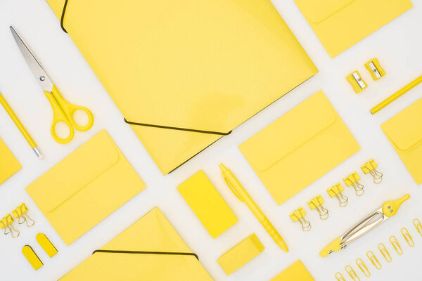 top view of yellow pen, pencils, paper clips, eraser, stickers, envelopes, stickers, folders, scissors, pencil sharpeners and compasses isolated on white