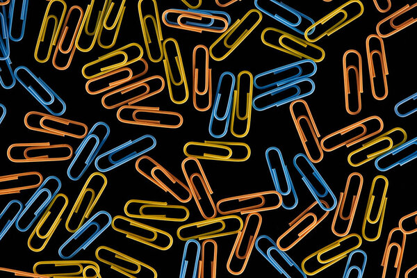 top view of colorful scattered paper clips isolated on black 