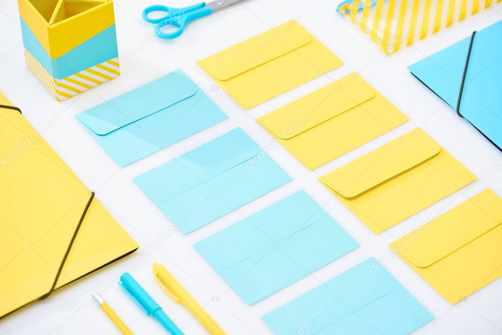 flat lay of blue and yellow envelopes and other stationery on white background
