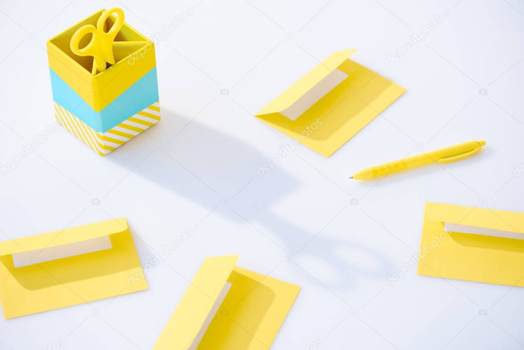 yellow envelopes and pen near pencil box with scissors on white background