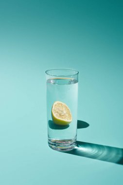 turkuaz arka plan üzerinde tatlı su ve limon ile şeffaf cam