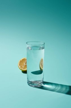 turkuaz arka plan üzerinde tatlı su ve sarı limon yarım şeffaf cam