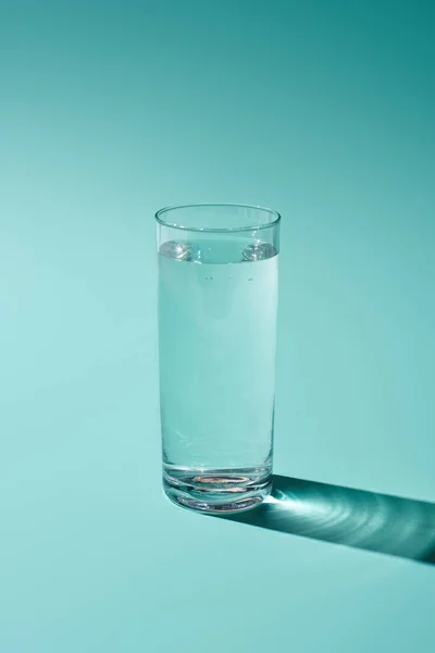 ターコイズ色の背景に水と透明なガラス — ストック写真