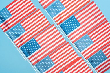 düz mavi arka plan üzerinde sopalar üzerinde Amerikan bayrakları ile yatıyordu