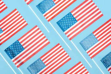 düz mavi arka plan üzerinde sopalarla ulusal Amerikan bayrakları ile yatıyordu