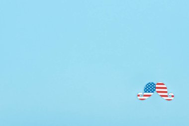top view of mustache made of american flag on blue background with copy space clipart