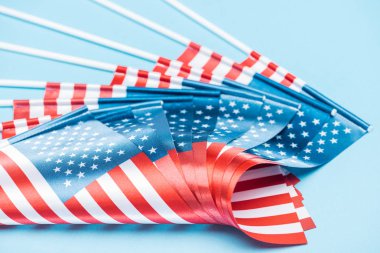 close up view of american flags on sticks on blue background clipart