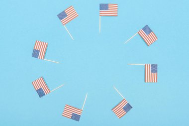 round frame made of paper cut decorative american flags on wooden sticks on blue background with copy space clipart