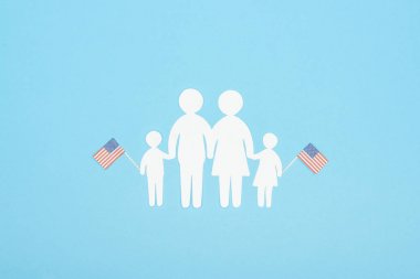 beyaz kağıt kesim aile mavi arka plan üzerinde ahşap çubuklar üzerinde dekoratif amerikan bayrakları tutan üst görünümü