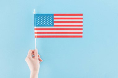 mavi arka plan üzerinde sopa üzerinde ulusal amerikan bayrağı tutan kadın kırpılmış görünümü
