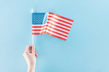 mavi arka plan üzerinde sopa üzerinde ulusal amerikan bayrağı tutan kadın kısmi görünümü