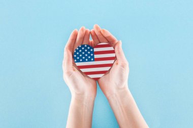 mavi arka plan üzerinde ulusal Amerikan bayrağı yapılmış kalp tutan kadın kırpılmış görünümü