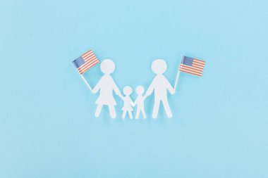 top view of  paper cut family holding decorative american flags on wooden sticks on blue background clipart