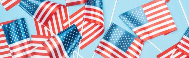 mavi arka plan üzerinde sopalarla dağınık Amerikan bayrakları panoramik çekim