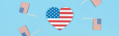 panoramic shot of heart made of stars and stripes near decorative american flags on wooden sticks on blue background clipart