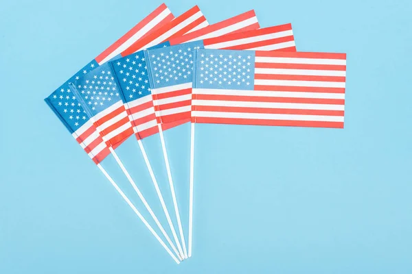 top view of american flags on sticks on blue background