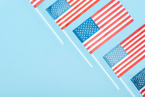 flat lay with american flags on sticks on blue background with copy space