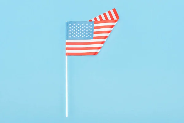 top view of american flag on stick on blue background