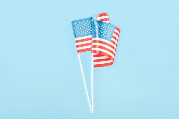 top view of two american flags on sticks on blue background