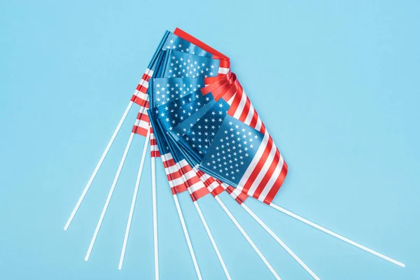 top view of shiny american flags on sticks on blue background