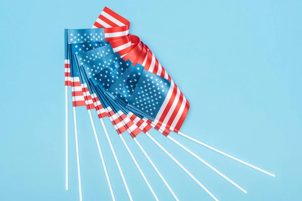 top view of american flags on sticks on blue background
