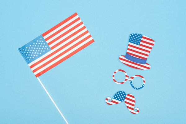 top view of usa flag on stick near paper cut mustache, hat and glasses on blue background