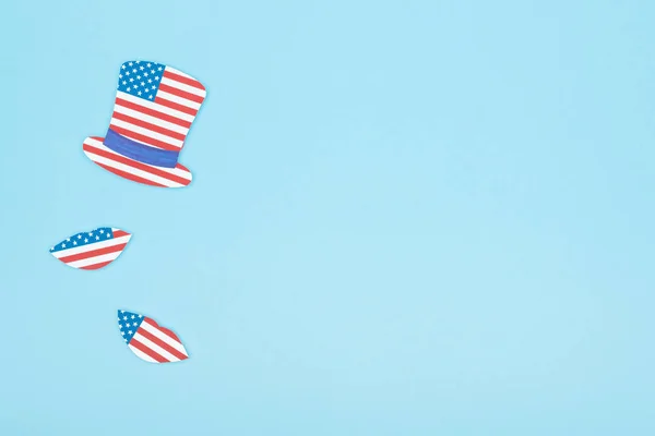 top view of paper cut mustache and lips made of usa flags on blue background with copy space