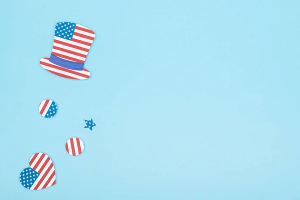 top view of paper cut decorative hat, star, circles and heart made of american flags on blue background with copy space