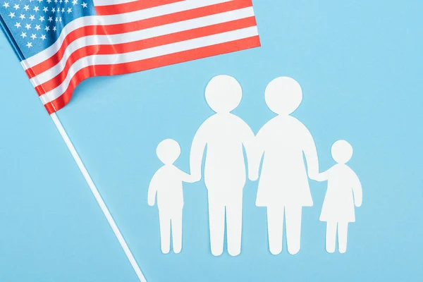 close up view of paper cut family and american flag on blue background