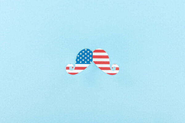 top view of paper cut decorative mustache made of american flag on blue background 