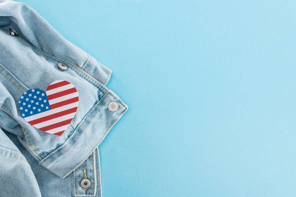 top view of paper cut heart made of american flag on denim stylish jacket on blue background with copy space