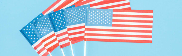 panoramic shot of american flags on sticks on blue background 