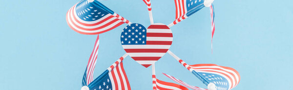 top view of american flags in circle with heart on blue background, panoramic shot 