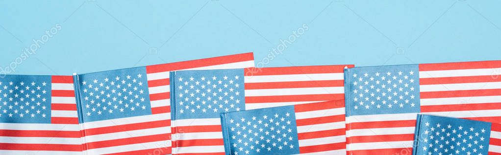 panoramic shot of national patriotic american flags on blue background